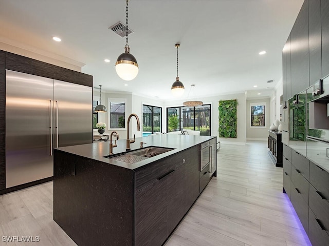 kitchen featuring a spacious island, sink, pendant lighting, light hardwood / wood-style floors, and built in refrigerator