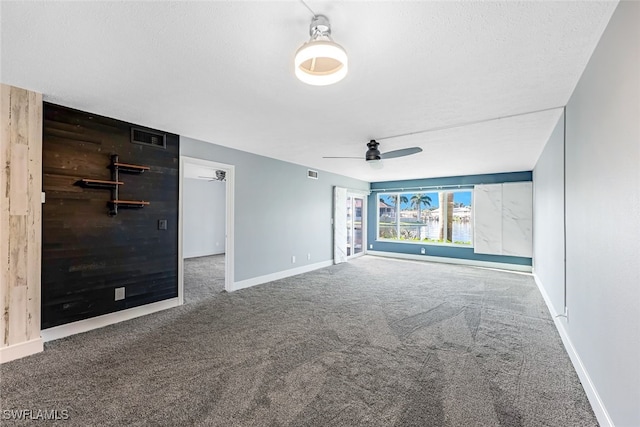 carpeted spare room featuring a ceiling fan, visible vents, and baseboards