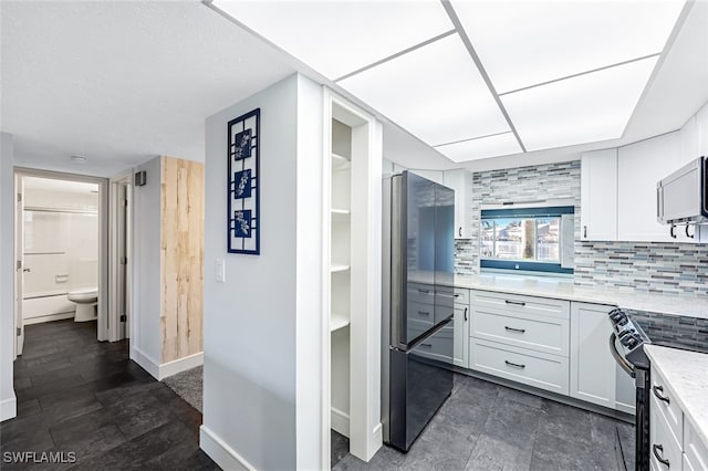 kitchen with decorative backsplash, black range with electric cooktop, white cabinetry, and freestanding refrigerator