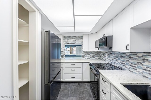 kitchen featuring backsplash, black range with electric stovetop, white cabinetry, and freestanding refrigerator