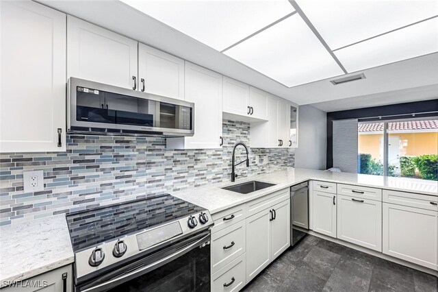 kitchen featuring visible vents, a sink, stainless steel appliances, white cabinets, and decorative backsplash