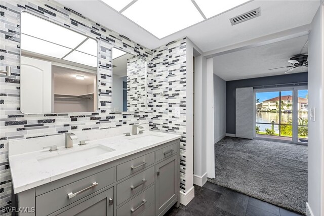 bathroom with visible vents, backsplash, ceiling fan, and a sink