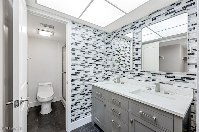 bathroom featuring double vanity, a shower stall, toilet, and a sink