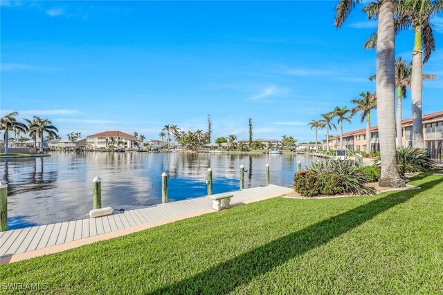 view of dock with a lawn and a water view