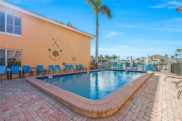 community pool with a patio area and fence