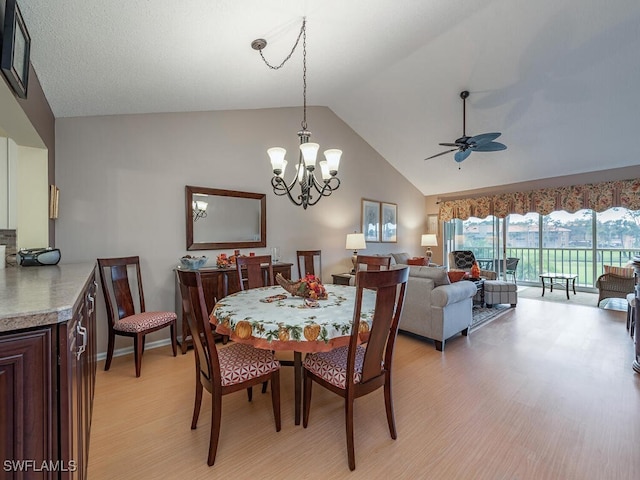 dining area featuring ceiling fan with notable chandelier, light hardwood / wood-style floors, and lofted ceiling