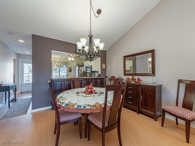 dining room featuring ceiling fan with notable chandelier, light hardwood / wood-style flooring, and lofted ceiling