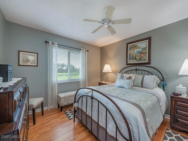 bedroom featuring ceiling fan, light hardwood / wood-style floors, and a textured ceiling