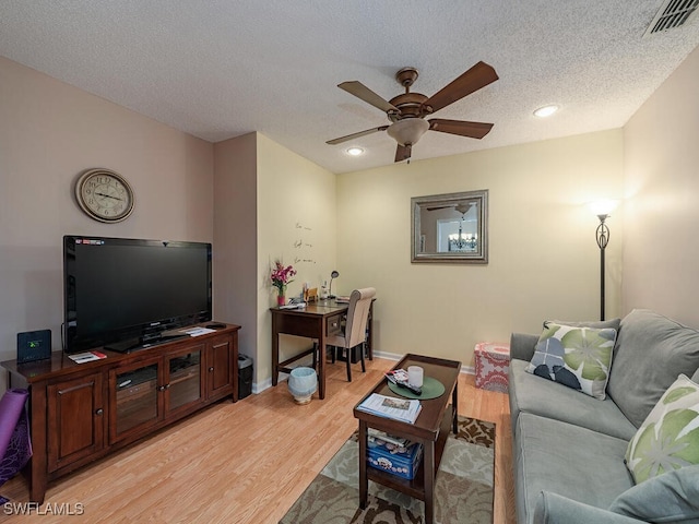 living room with a textured ceiling, light wood-type flooring, and ceiling fan