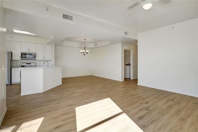 kitchen with pendant lighting, white cabinets, ceiling fan with notable chandelier, appliances with stainless steel finishes, and light hardwood / wood-style floors