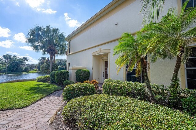26414 Lucky Stone Rd Unit 101, Bonita Springs, FL 34135 - view of exterior entry featuring stucco siding, a water view, and a yard