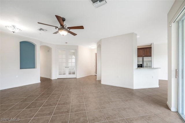 unfurnished living room featuring light tile patterned flooring, ceiling fan, and french doors