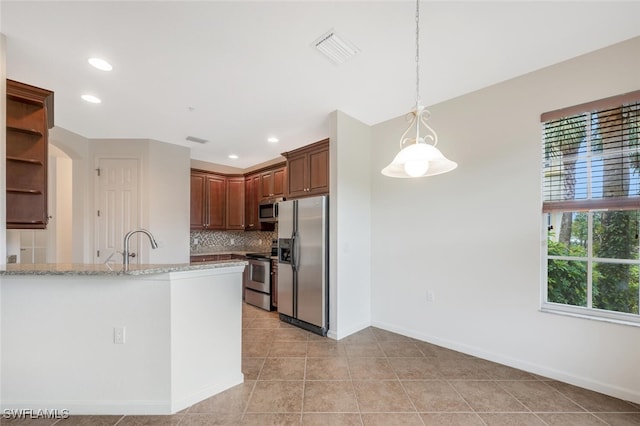 kitchen featuring hanging light fixtures, kitchen peninsula, stainless steel appliances, light stone countertops, and decorative backsplash