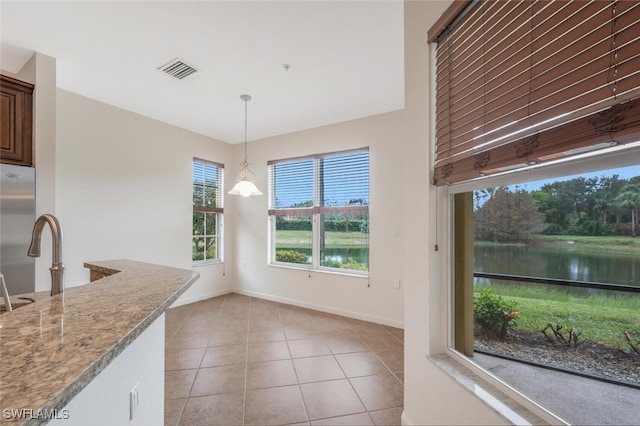 unfurnished dining area featuring a water view, sink, and light tile patterned floors