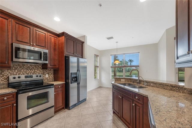 kitchen featuring pendant lighting, sink, stainless steel appliances, and light stone countertops