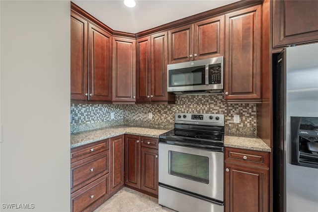 kitchen with light tile patterned flooring, appliances with stainless steel finishes, light stone counters, and decorative backsplash