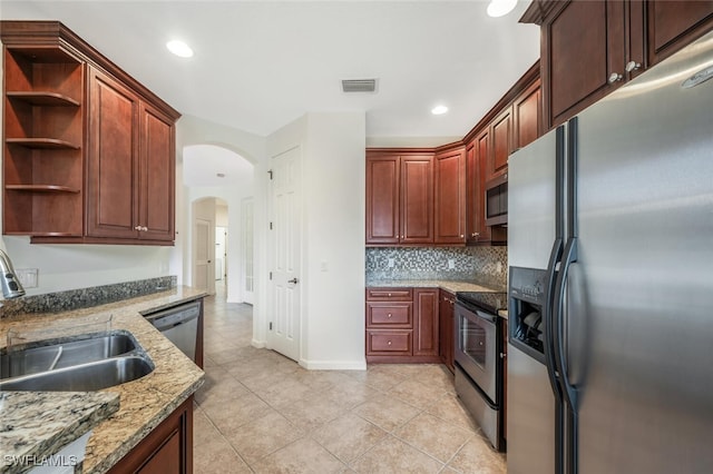 kitchen featuring light tile patterned flooring, sink, appliances with stainless steel finishes, light stone countertops, and decorative backsplash