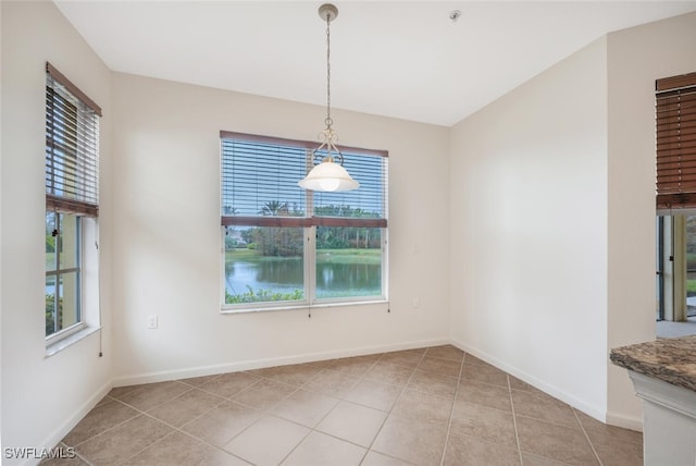 unfurnished dining area with a water view and light tile patterned floors