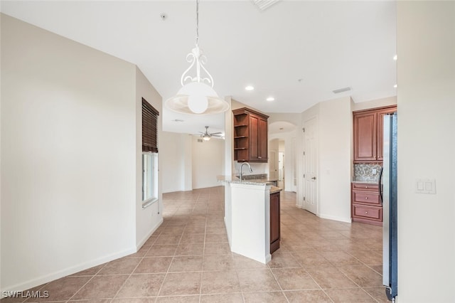 kitchen with pendant lighting, sink, stainless steel refrigerator, tasteful backsplash, and light tile patterned flooring