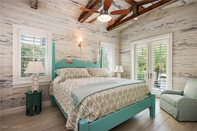 bedroom with vaulted ceiling with beams, hardwood / wood-style flooring, and multiple windows