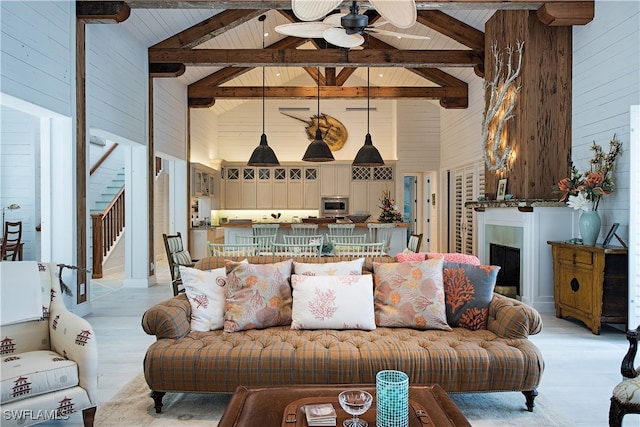 living room featuring beam ceiling, light wood-type flooring, and high vaulted ceiling