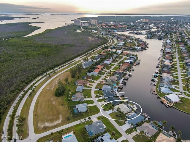 aerial view at dusk featuring a water view