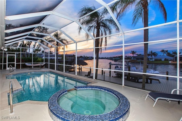 pool at dusk featuring a lanai, a water view, an in ground hot tub, and a patio