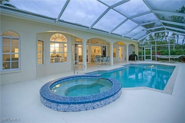 view of pool featuring glass enclosure, a patio area, and an in ground hot tub