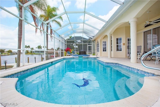 view of swimming pool with glass enclosure, a patio area, ceiling fan, and a water view