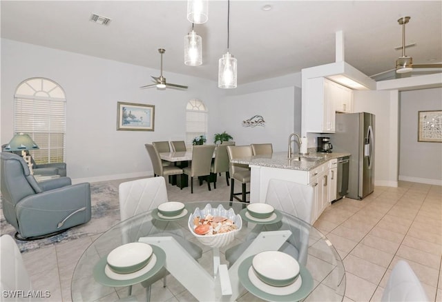 tiled dining space featuring ceiling fan and sink