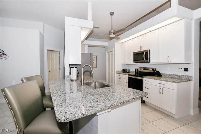 kitchen with light stone countertops, sink, stainless steel appliances, and white cabinetry