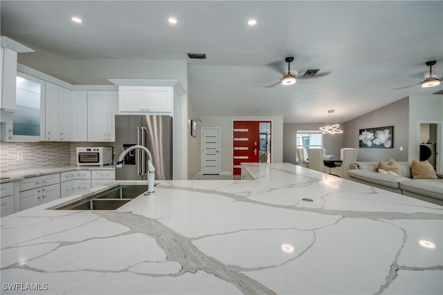 kitchen with sink, tasteful backsplash, high end fridge, white cabinets, and ceiling fan with notable chandelier