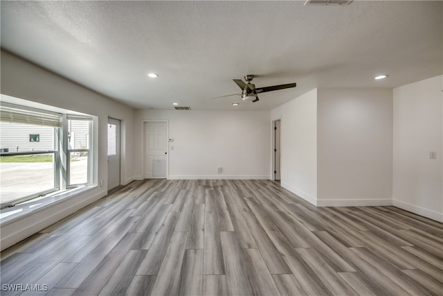 spare room with a textured ceiling, light hardwood / wood-style floors, and ceiling fan