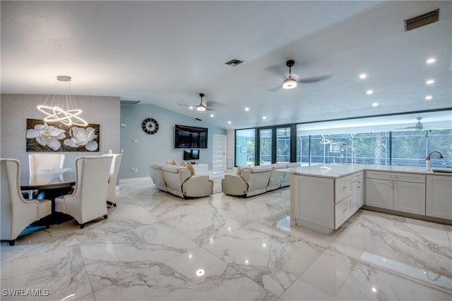 kitchen with plenty of natural light, white cabinets, pendant lighting, and ceiling fan with notable chandelier