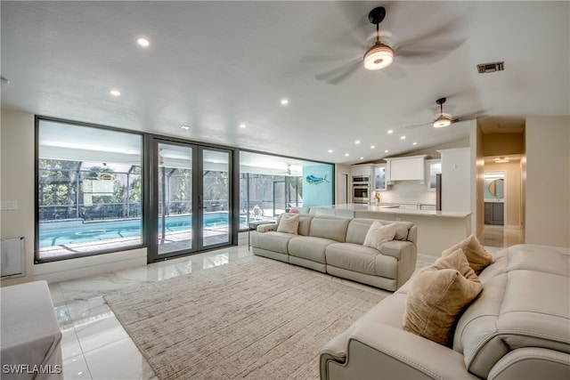 living room with ceiling fan, french doors, expansive windows, and vaulted ceiling