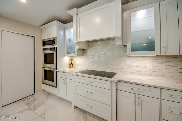 kitchen featuring backsplash, light stone counters, a textured ceiling, stainless steel appliances, and white cabinets