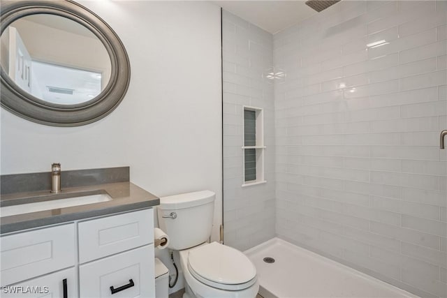 bathroom with vanity, toilet, and a tile shower