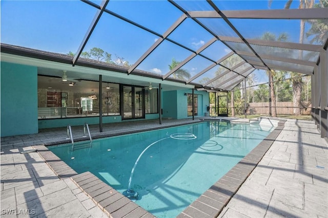 view of swimming pool with a patio area, ceiling fan, and glass enclosure