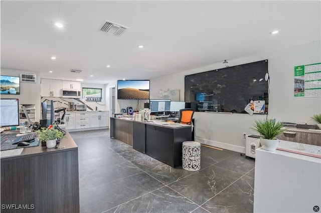 interior space with a kitchen island with sink, light stone countertops, and white cabinets