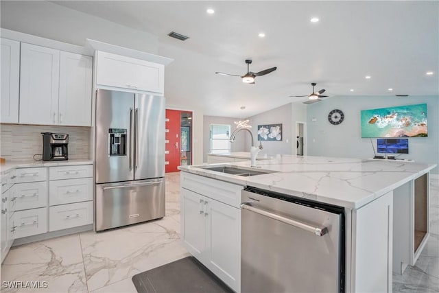 kitchen featuring stainless steel appliances, an island with sink, sink, and white cabinets