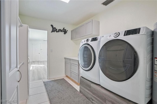 laundry room featuring cabinets, washing machine and dryer, and light tile patterned floors