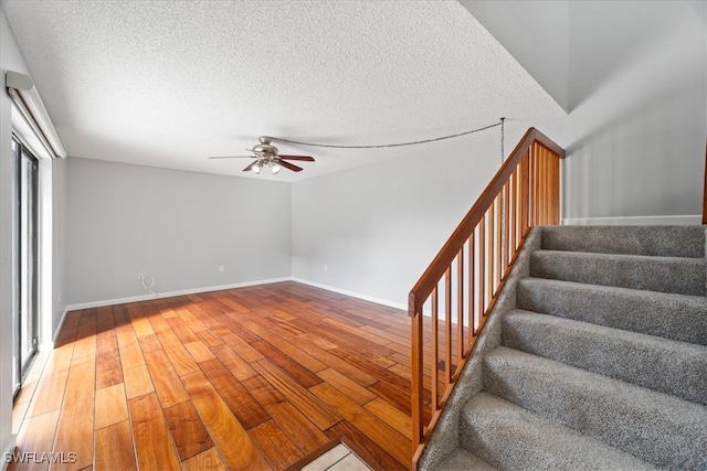 stairway featuring hardwood / wood-style floors, a textured ceiling, plenty of natural light, and ceiling fan