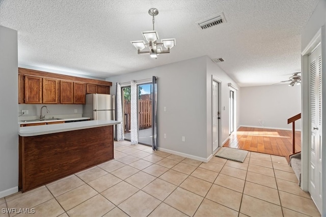 kitchen featuring decorative light fixtures, stainless steel fridge, light hardwood / wood-style floors, and a textured ceiling