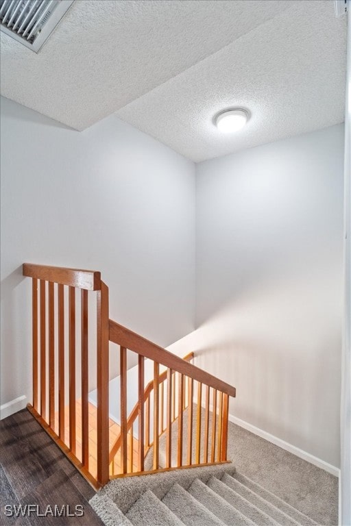 staircase featuring carpet flooring and a textured ceiling