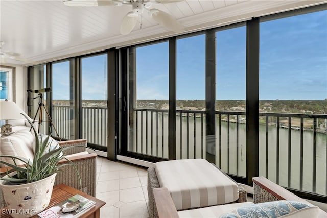 sunroom with ceiling fan and a water view