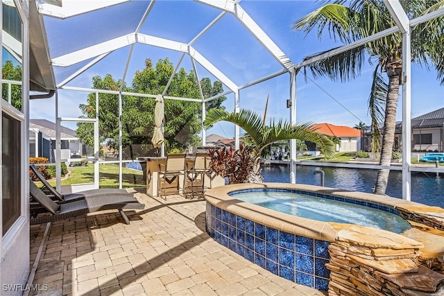 view of patio with an in ground hot tub, a water view, an outdoor bar, and a lanai