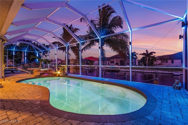 pool at dusk with a lanai, a water view, and a patio