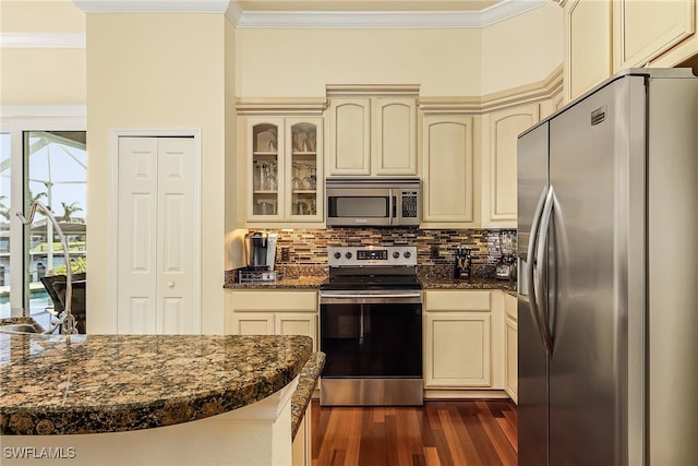 kitchen featuring cream cabinets, dark hardwood / wood-style flooring, stainless steel appliances, and crown molding