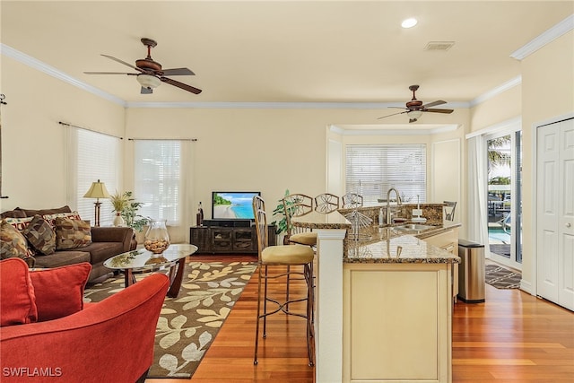 living room featuring crown molding, sink, ceiling fan, and light hardwood / wood-style floors