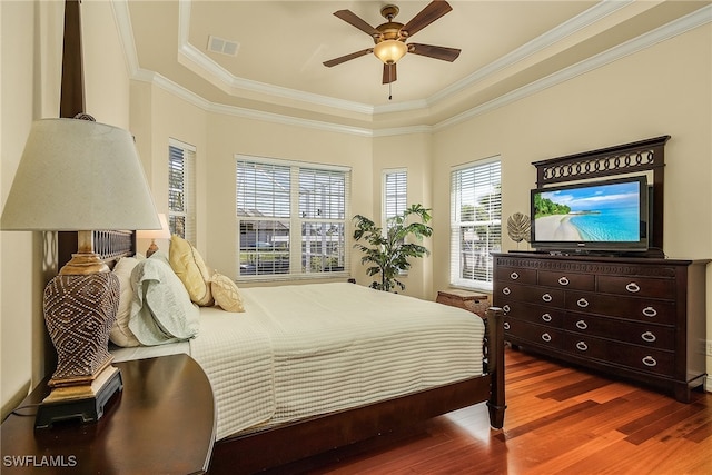 bedroom featuring a tray ceiling, ceiling fan, ornamental molding, and hardwood / wood-style flooring